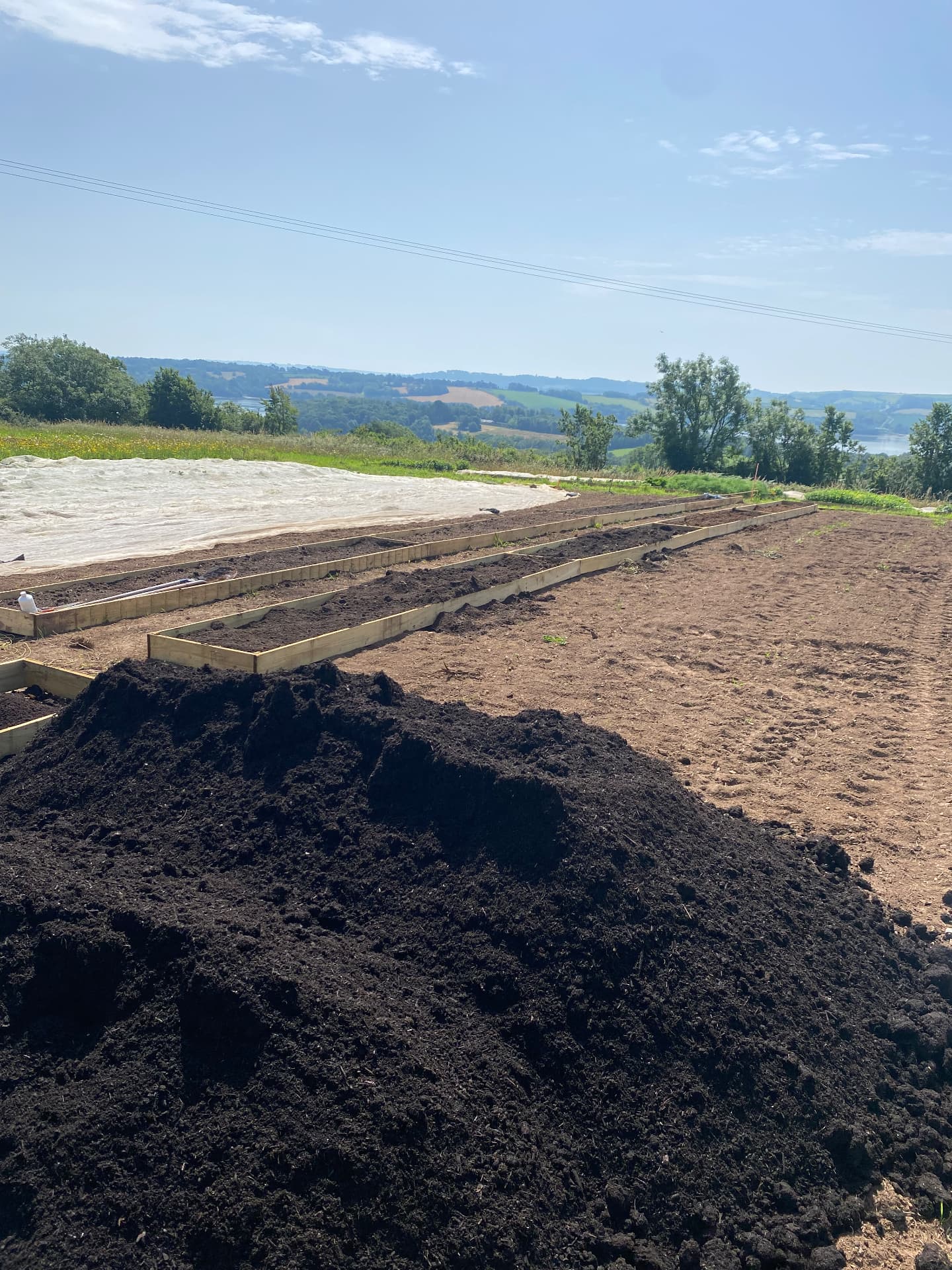 Tipped compost load next to newly filled raised beds overlooking the Tamar valley